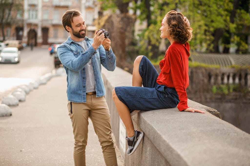 Woman posing on a bridge while man takes her photo